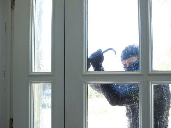 Cambrioleur qui essaie d'ouvrir une fenêtre avec un pied-de-biche
