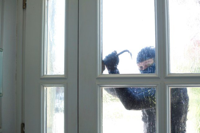 Cambrioleur qui essaie d'ouvrir une fenêtre avec un pied-de-biche